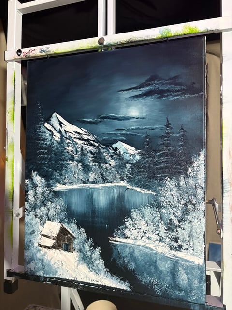 Painting of a snowy mountain landscape with a frozen lake, cabin, and evergreen trees under moonlight