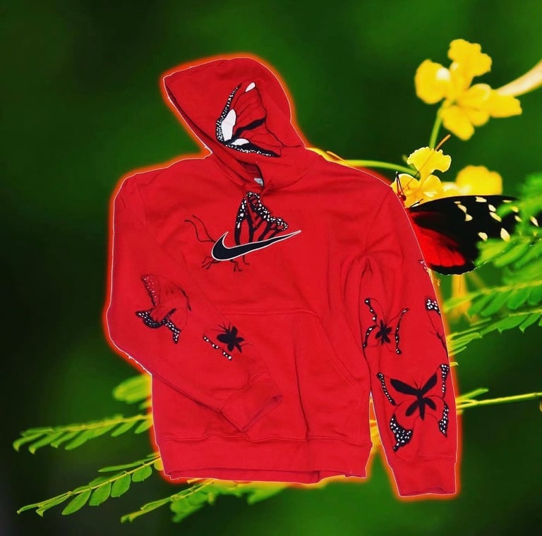 Red hoodie with black spider designs on green background with yellow flowers