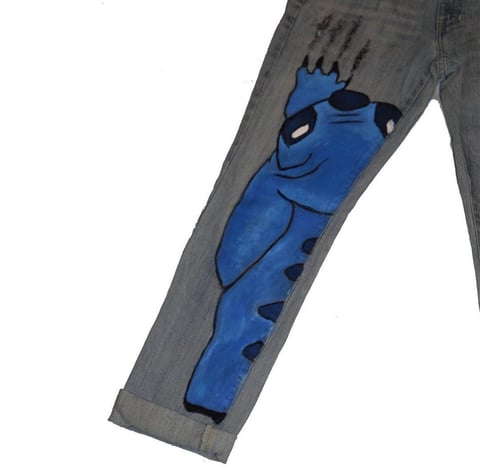 Blue cartoon character printed on gray pant leg, showing friendly creature with spiky hair and spotted body