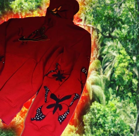 Person wearing vibrant red fabric with black star embellishments against blurred green foliage background
