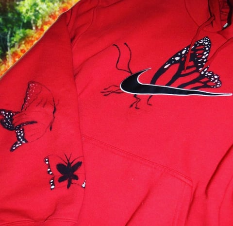 Three decorative insects with black and white patterned wings on a red fabric background