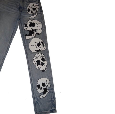 Pair of blue jeans with white skull graphics printed vertically down the leg