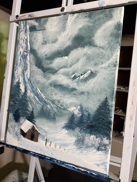 Painting of a snowy mountain landscape with evergreen trees, a small cabin, and snow-covered peaks with dramatic cloudy sky